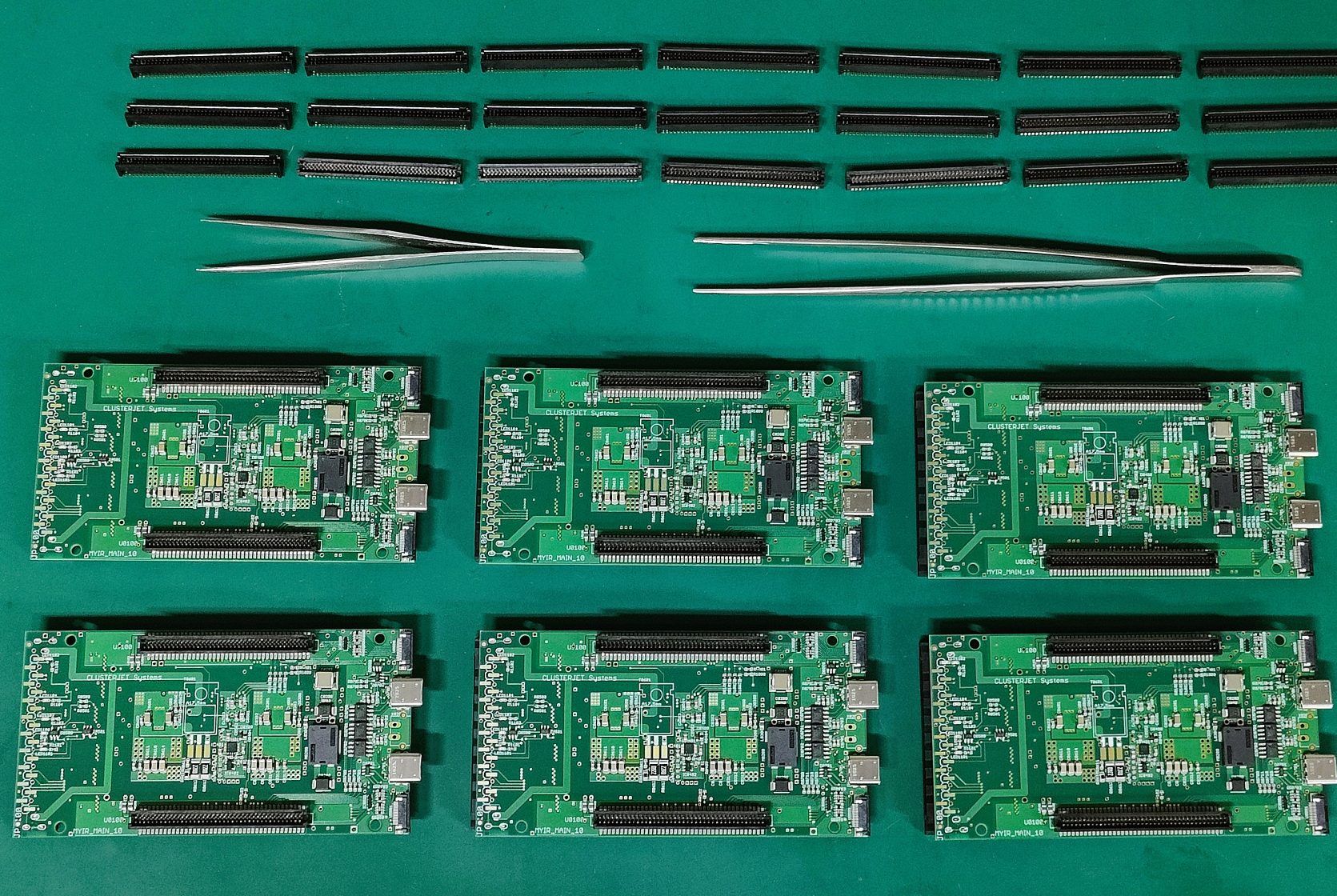 Sechs grüne Leiterplatten und einige schwarze Stiftleisten auf einer ESD-Schutzmatte.
